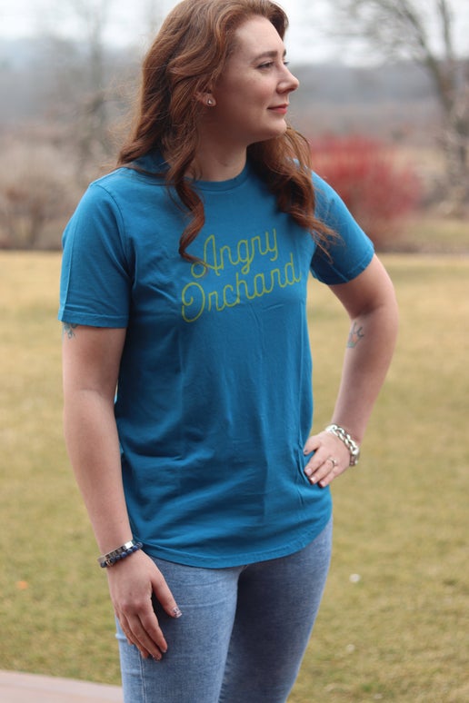 Front of blue tee displays yellow writing "Angry Orchard" in script.