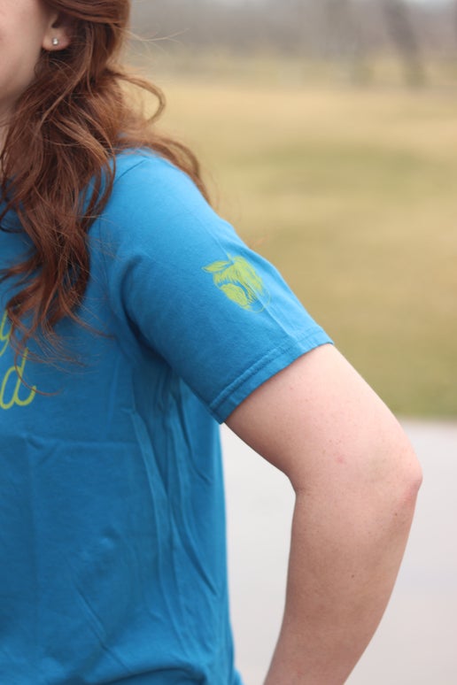 Left sleeve displays small yellow silhouette of Angry Orchard iconic bitten apple.