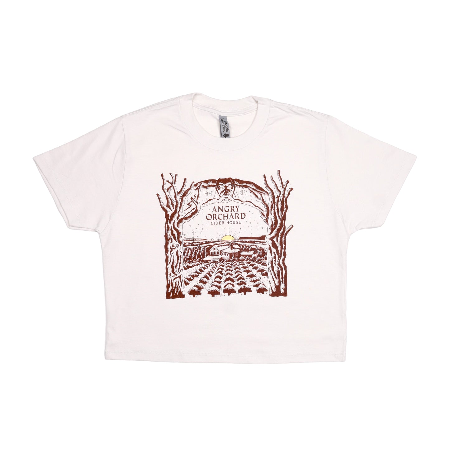 Angry Orchard Cider House design in dark red print on a white bone short sleeve T-shirt. The design is a hand drawn like image of the cider house sitting in the orchard, with a small yellow sun setting on the horizon. Bordering the sides of this image are two trees that form an arch over the top border imagery. In the center of this imagery reads "Angry Orchard, Cider House" in the classic angry orchard font.