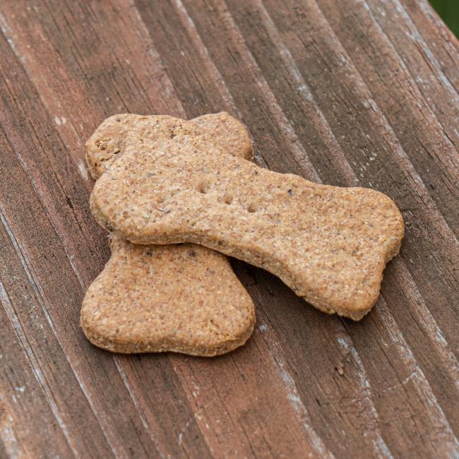 Two Waggies Peanut Butter 2 Pack Dog Treats from Waggies by Maggie & Friends rest on a rustic wooden surface—perfect for pampering your pup.