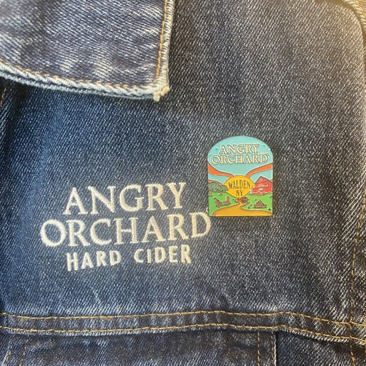 Pin features "Angry Orchard" written at the top of pin and Walden, NY in the center. Design on pin is Angry Orchard orchard in Walden.