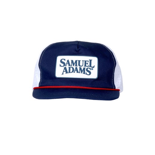 A navy trucker hat with red rope piping and a white Samuel Adams patch on the front.