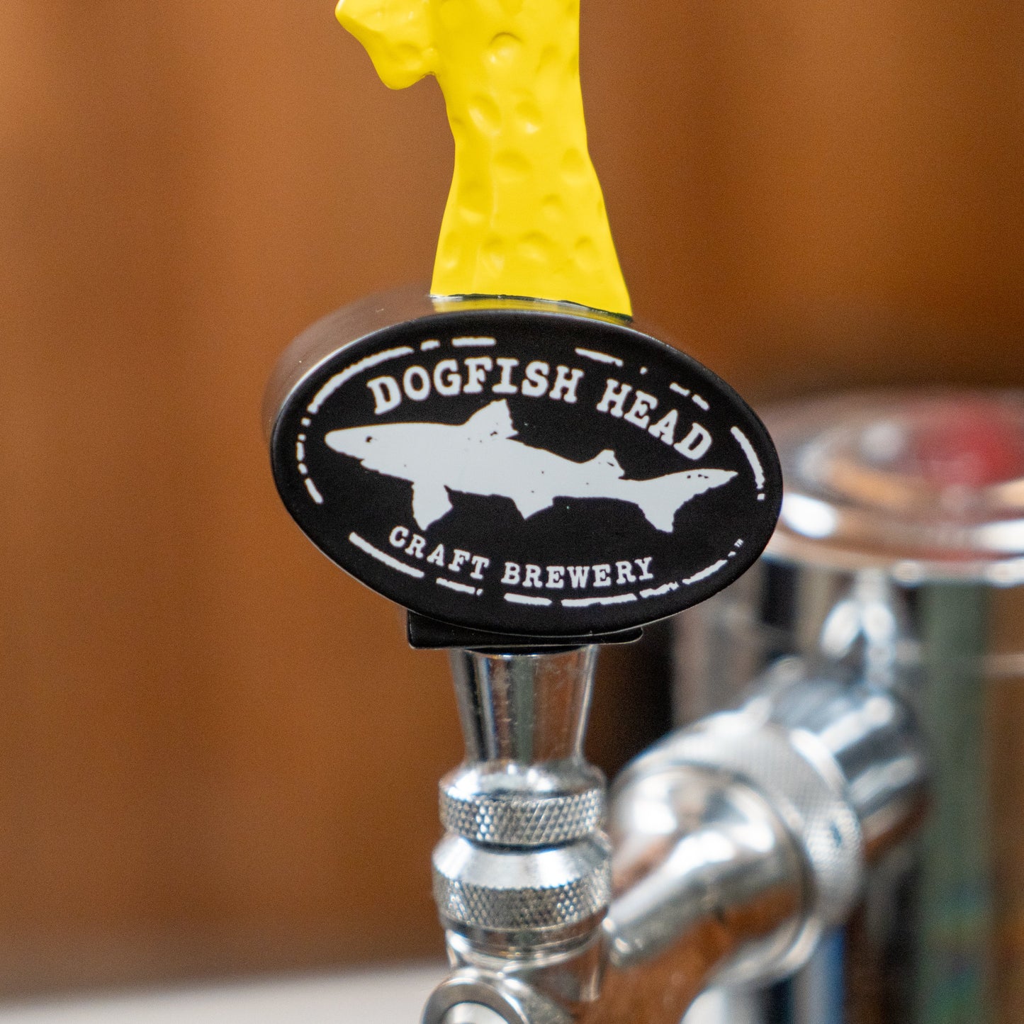 Introducing the Yellow Shark Tap Handle Shorty by Merchtank—a short beer tap handle with a neon yellow top and a black oval label reading Dogfish Head Craft Brewery, securely attached to a polished metal tap. Perfect for serving your favorite Dogfish beers in style.