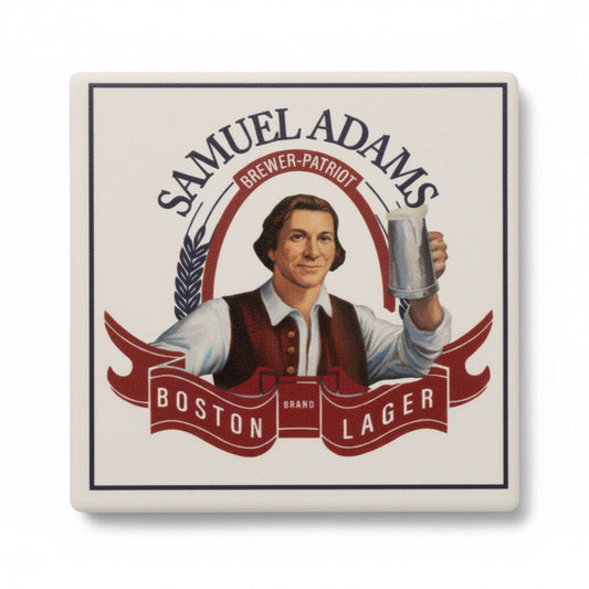 a top view of a coaster, with curved Sam Adams text at the top, "Brewer Patriot" written underneath the top text. Featuring a colonial dressed person raising a stein. "Boston Lager" is written in white within in a flag shape at the bottom. 